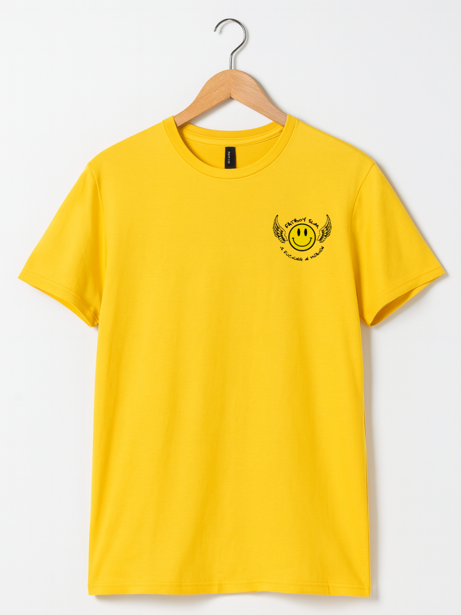 A bright yellow short-sleeve t-shirt hanging on a wooden hanger against a light gray background. The shirt features a small black graphic on the left chest depicting a smiley face inside a winged circle with the text 'Smiling Faces' and 'Proud to Be'.