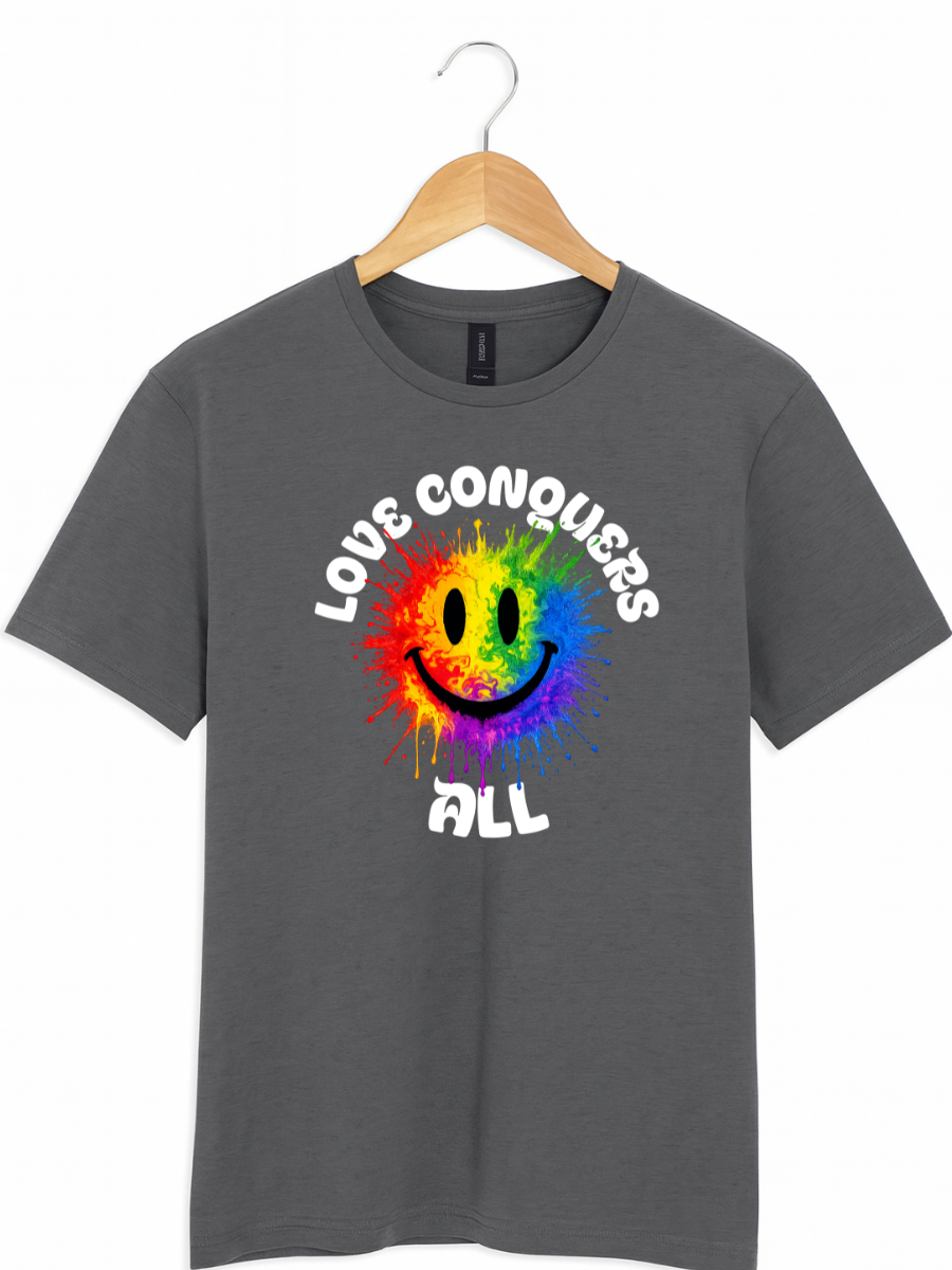 A dark grey crewneck t-shirt hanging on a wooden hanger against a white background. The shirt features a colorful graphic of a rainbow smiley face with the words 'LOVE CONQUERS' above it and 'ALL' below it in white stylized text.