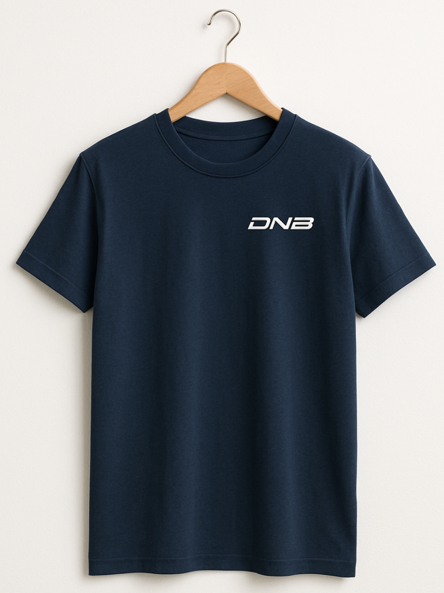 A navy blue short-sleeve crewneck t-shirt hanging on a wooden hanger against a light beige wall. The shirt features a small white 'DNB' logo printed on the left chest.