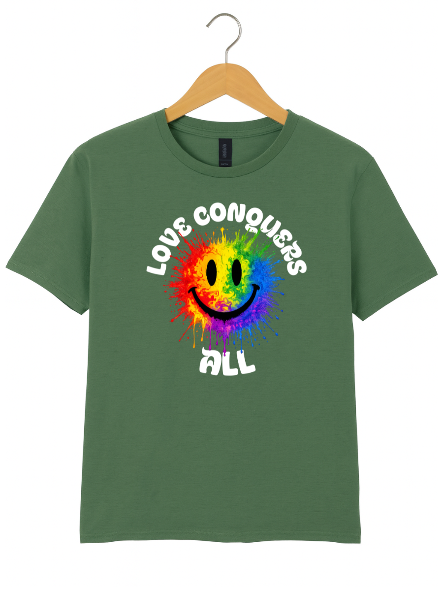 A green short-sleeve t-shirt hanging on a wooden hanger against a white background, featuring a colorful rainbow smiley face graphic with the words 'LOVE CONQUERS ALL' in white.