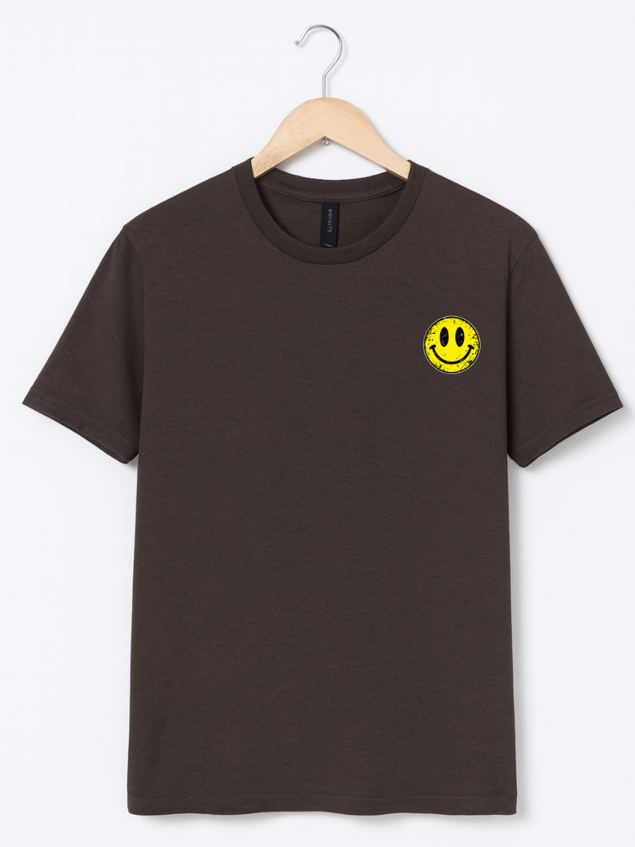 A dark brown short-sleeve crewneck t-shirt hanging on a wooden hanger against a light gray background. The shirt features a small yellow smiley face graphic on the left chest.